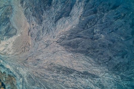Aerial abstract of a toxic industrial waste dam. Shelling craters are visible across the intricate...