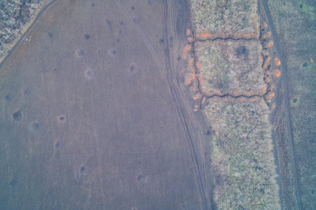Aerial drone shot of a defensive stronghold inside a small forest patch near plowed fields. Top down view of military earthworks, trench lines and logistic tracks in Ukraine.の写真素材