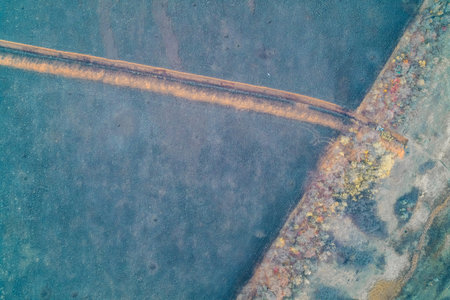 Aerial drone shot of a long straight anti-tank ditch filled with orange clay running perpendicular...