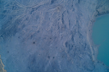 Aerial drone shot of chemical sediment forming complex dendritic drainage patterns near a cyan...