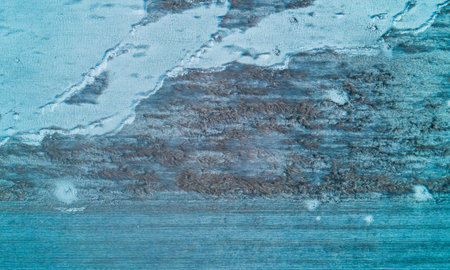 Frosty agricultural field reveals a mesmerizing abstract pattern of fresh snow and withered brown...