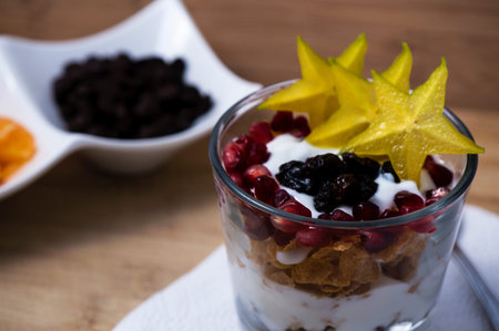 A glass with yogurt cereals and fruits on wooden background