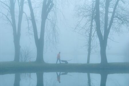 The gardener on coast of lake. Earlier morning. A fogの写真素材