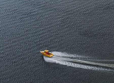 The yellow boat rushing on a surface of the sea.の写真素材