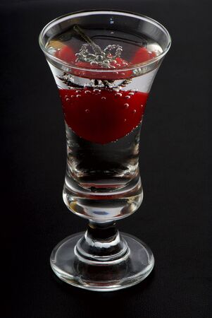 Tomato in a wine-glass. A black background. Studio shootingの写真素材