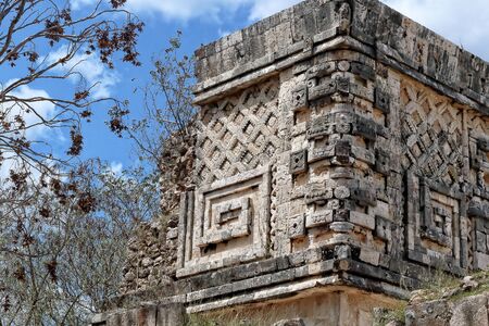 An image of an architectural detail of Puuc style, in the very old Mayan city of Uxmal, as background and background, vegetation, blue sky and clouds, color. Yucatan. Mexicoの写真素材