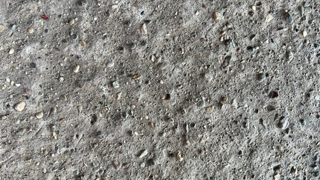 Close-up view of a concrete surface showing its rough texture and embedded stones.の写真素材