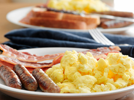 breakfast meal with sausage and scrambled eggs with bacon.