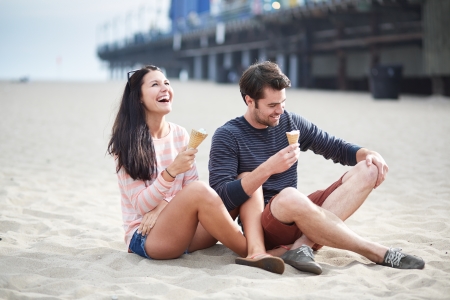 couple sitting in sand at sant monica pier.の写真素材