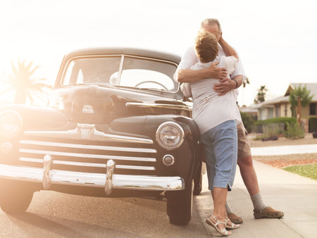 senior couple with vintage car kissingの写真素材