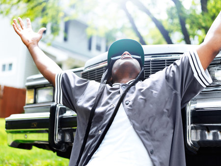 young black man in front of car with arms out