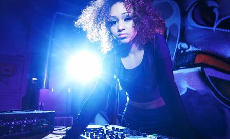 female club dj using turntable with headphones with lens flareの写真素材
