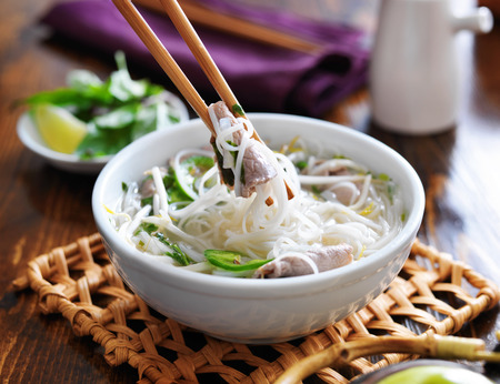 eating a bowl of pho with noodles and beefの写真素材