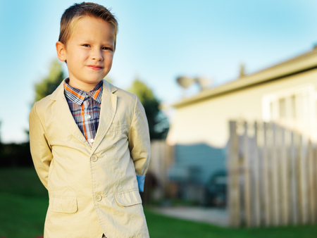 little schoolboy posing outside in front of homeの写真素材