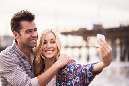 cute couple taking selfies together on beachの写真素材