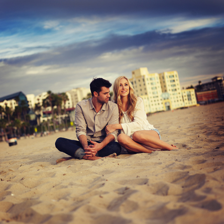 cute couple on beach cuddling while watching sunsetの写真素材