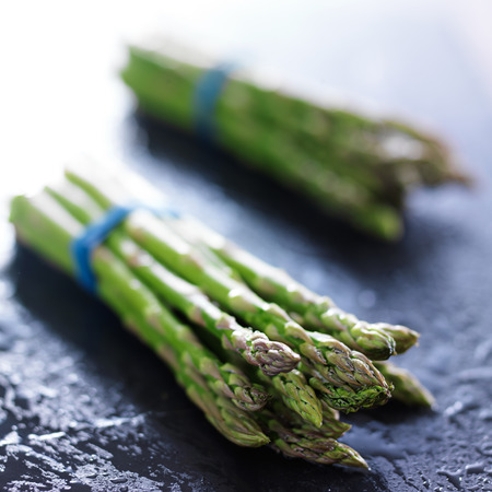 side view of two bunches of fresh asparagusの写真素材