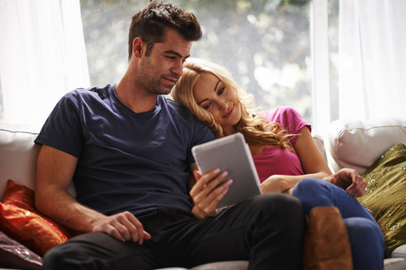 couple watching videos or shopping on tablet togetherの写真素材