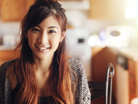 happy smiling asian teen girl portrait in kitchenの写真素材