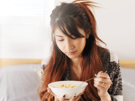 asian teen girl eating chicken noodle soupの写真素材