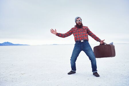 insane widly screaming hipster with awesome beard and retro suitcase making extreme motions on desolate empty salt flatsの写真素材