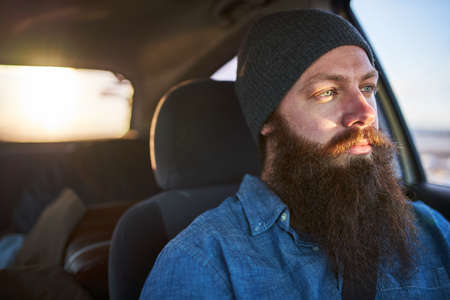 bearded guy driving car on road tripの写真素材