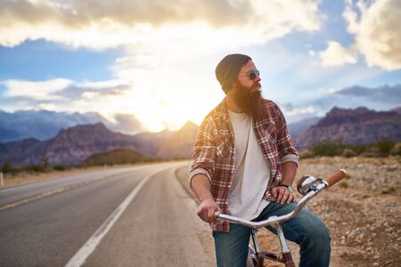man on side of road riding bike at sunset in nevadaの写真素材