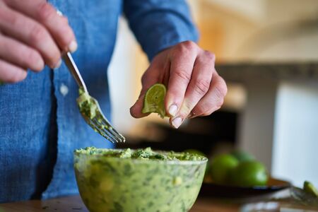 adding lime juice to guacamoleの写真素材