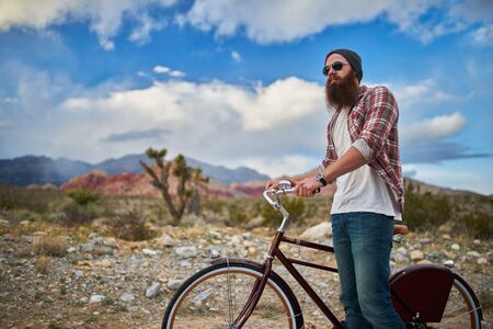 man stopped on bike in nevada desert beside redrockの写真素材