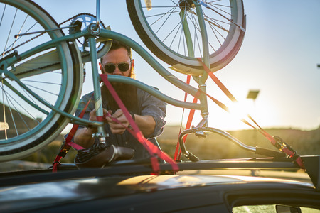 man checking straps on bike rackの写真素材