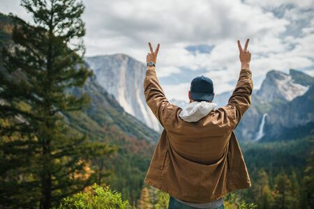 man in winter coat cheering infront of yosemiteの写真素材
