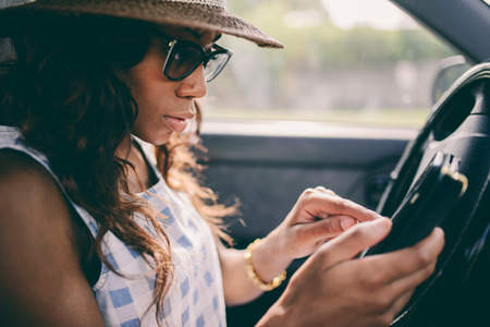 Woman Using Mobile Phone While Driving Car with low contrast filterの写真素材