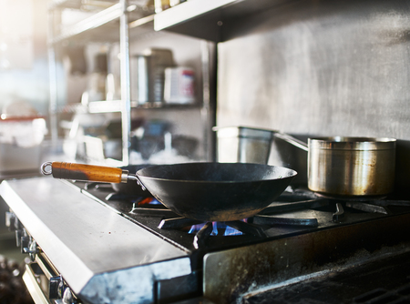 wok on gas stove getting hot in commercial restaurant kitchenの写真素材