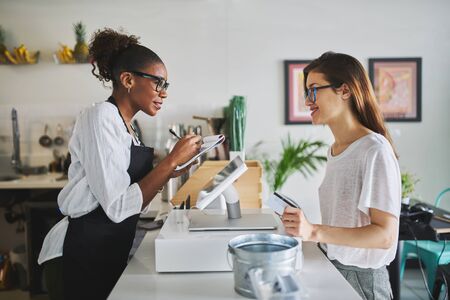 friendly african american waitress taking order on notepad from customerの写真素材