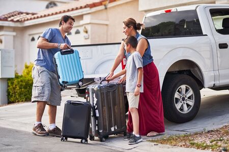 hispanic family packing luggage into pickup truck in front of houseの写真素材