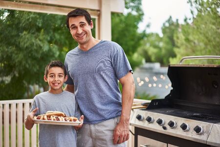 proud father and son showing tray of grilled hot dogsの写真素材
