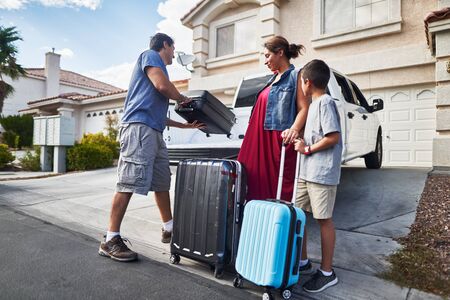 hispanic family packing luggage into pickup truck in front of houseの写真素材