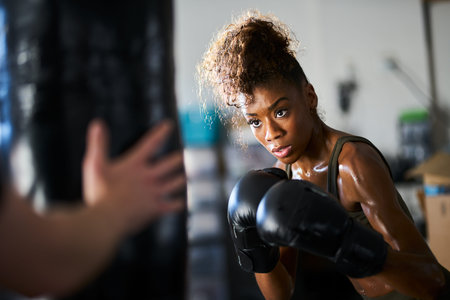 african woman boxing with punching bag in garage gym