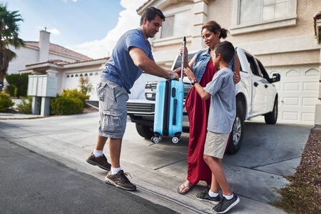 hispanic family packing luggage into pickup truck in front of houseの写真素材