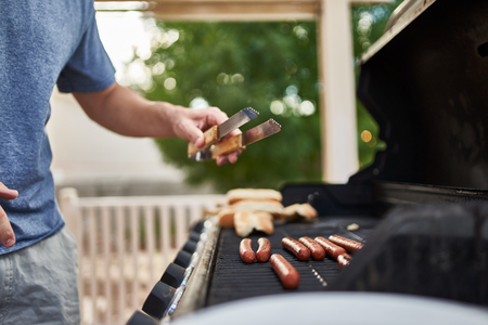 man grilling hot dogs on grill during the dayの写真素材