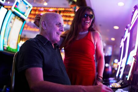 elderly couple gambling on slot machine in casinoの写真素材