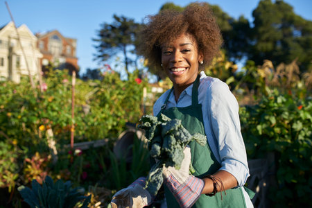 Proud diverse millennial posing with freshly picked kale at urban community communal garden