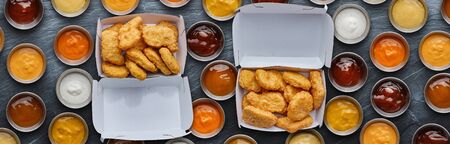 two boxes of fast food fried chicken nuggets with different dipping saucesの写真素材