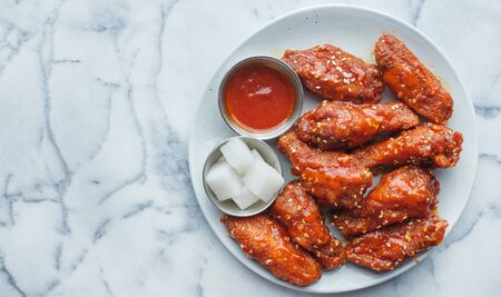 Korean fried chicken wings in gochujang sauce with pickled radish and Kimchiの写真素材