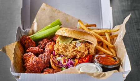 take out box with fried chicken sandwich, boneless wings and french friesの写真素材