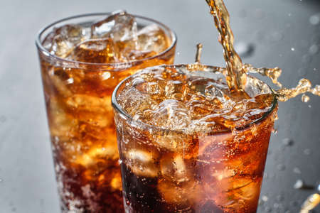 two cups of cola soft drink being poured into glassの写真素材