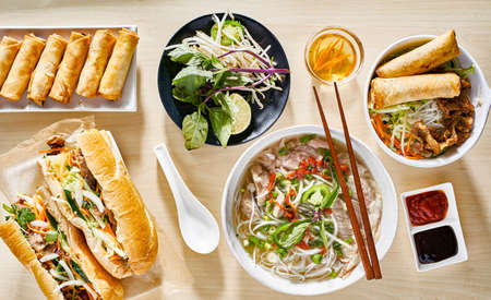 assorted vietnamese dishes with pho, bahn mi, spring rolls in top down composition on dinner tableの写真素材