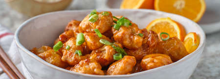 bowl of chinese orange chicken on table topの写真素材