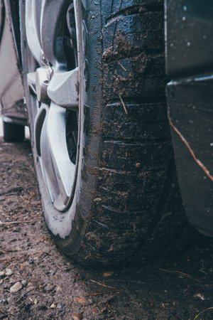 Close-up of the wheel of a black car covered with mud. autumn dirt slush car wheel dirty road forest path off-road passenger car summer tiresの写真素材