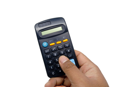 A hand is holding and pressing buttons on a dark-colored calculator with yellow and blue accents, isolated against a bright white background, conveying action in calculation or accounting.の写真素材